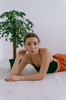 Portrait of young caucasian woman in red cloth laying near flowerpot. Dreamy