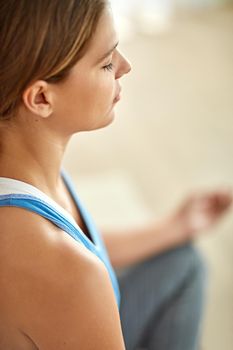Cropped shot of a woman meditating indoors.