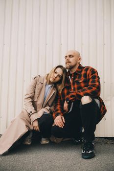 Loving couple stand near wall and look in camera hipster