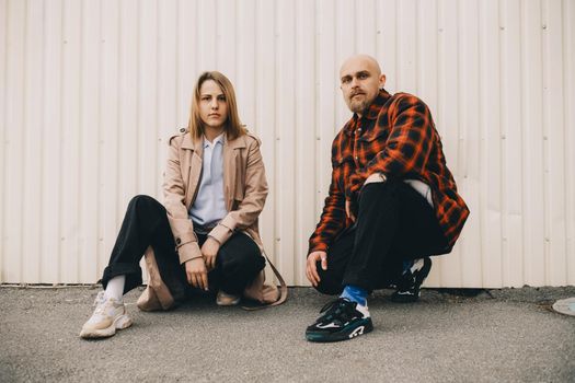 Loving couple stand near wall and look in camera hipster