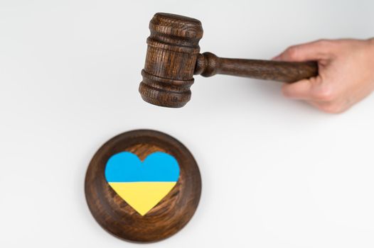 Woman hitting the judge's gavel on the heart with the flag of Ukraine on a white background
