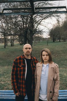 Portrait of a young white couple looking at the camera with suspicion. Outdoors