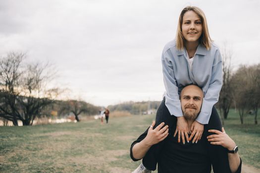 man carries a woman in his arms in the park and they have fun and happy