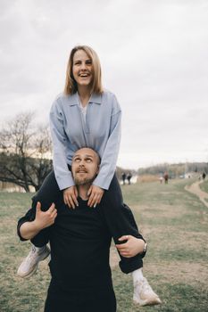 man carries a woman in his arms in the park and they have fun and happy