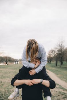 man carries a woman in his arms in the park and they have fun and happy