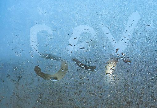 Closeup sign of sex on the foggy window glass with dripping drops condensated background, sensual steamy abstraction.