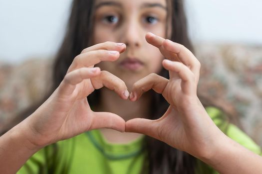 A cute Caucasian child holds a palm in the shape of a heart