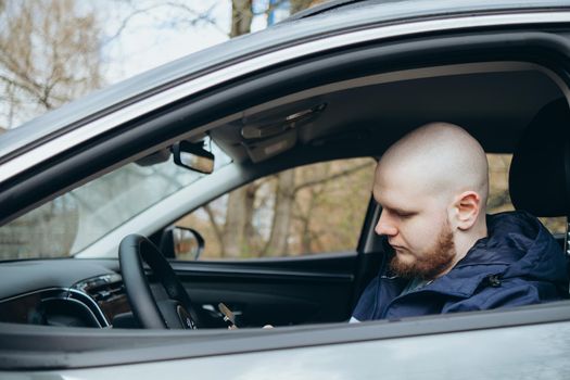 Handsome elegant bearded bald head serious man drives a car