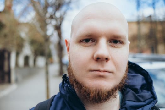 A white man with bald head and beard has a rest in a park, close-up.