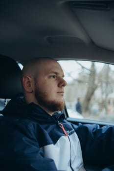 Handsome elegant bearded bald head serious man drives a car