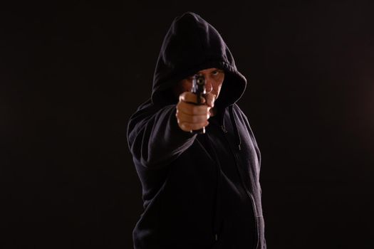 Man in black hoodie points handgun