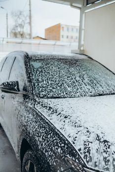 Automatic car wash in action. Great black car in the foam