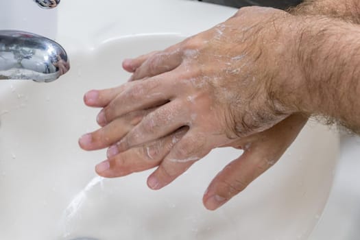 Man washing hands in basin close-up, one of several in handwashing steps series