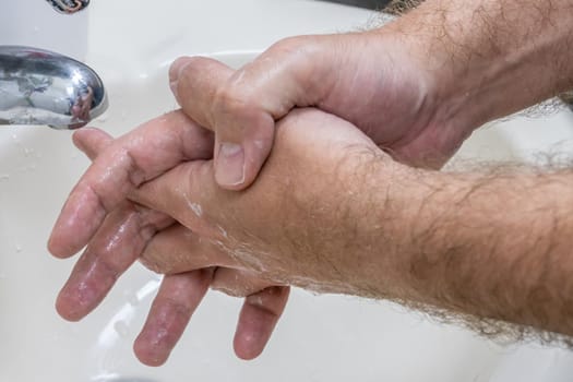 Man washing hands in basin close-up, one of several in handwashing steps series