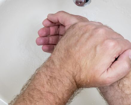 Man washing hands close-up from above, one of several handwashing steps for thorough cleaning