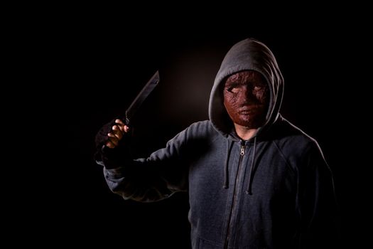Scary killer in mask and hoodie holding knife