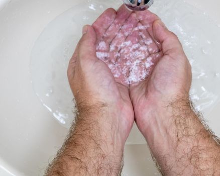 Man washing hands close-up from above, one of several handwashing steps for thorough cleaning