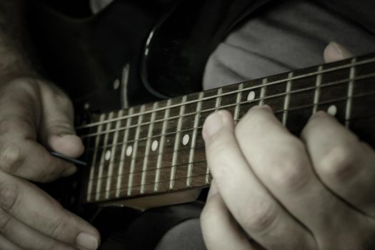 Close-up of man playing lead guitar solo on black guitar