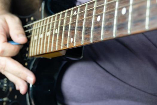 Close-up of man playing lead guitar solo on black guitar