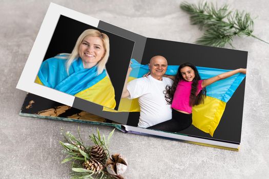 Family photos archive saved in brightly designed photo book; bright summer memories placed in the photobook. family with flag of ukraine.