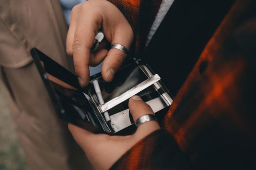 Male hand offering cigarettes, cigarette case.man's hands takes a cigarette out of pack.