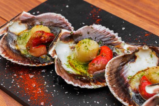 Cooked scallops on blackstone slate plate with species. Variety of mediterranean seafood