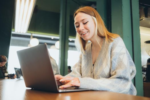 Girl working at her laptop sitting in the cafe happy