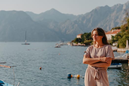 Girl tourist walking through ancient narrow street on a beautiful summer day in MEDITERRANEAN MEDIEVAL CITY , OLD TOWN bUDVA, MONTENEGRO. Young beautiful cheerful woman walking on old street at tropical town. Pretty girl looking at you and smiling