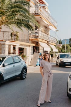 Girl tourist walking through ancient narrow street on a beautiful summer day in MEDITERRANEAN MEDIEVAL CITY , OLD TOWN bUDVA, MONTENEGRO. Young beautiful cheerful woman walking on old street at tropical town. Pretty girl looking at you and smiling