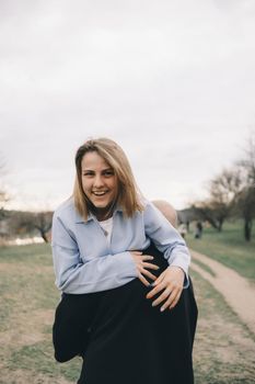 man carries a woman in his arms in the park and they have fun and happy