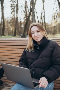 Smiling woman studying on laptop at park happy