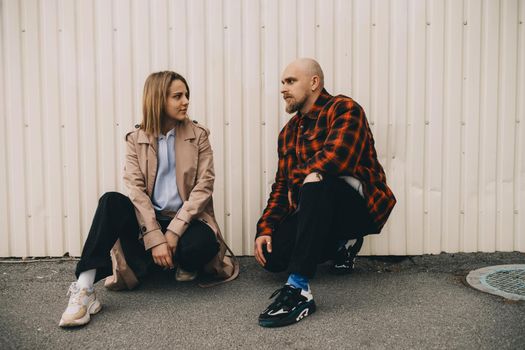 Loving couple stand near wall and look in camera hipster