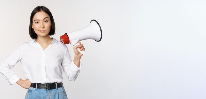 Image of modern asian woman with megaphone, making announcement, white background.