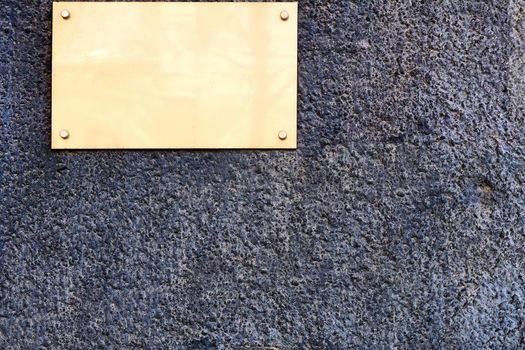 an ornamental tablet, typically of metal, porcelain, or wood, that is fixed to a wall or other surface in commemoration of a person or event.Plaque with place for text on granite wall.