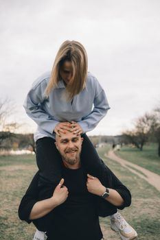 man carries a woman in his arms in the park and they have fun and happy