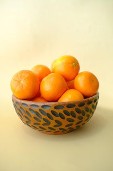 slice of orange fruits in a bowl on light yellow background .