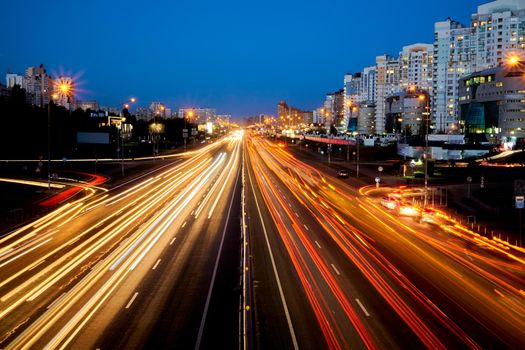 a broad road in a town or city, typically having trees at regular intervals along its sides. night shining avenue with moving cars and lights.