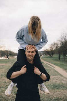 man carries a woman in his arms in the park and they have fun and happy