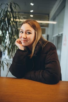 Young smiling attractive lady drinking coffee while ralxing in cafe indoors