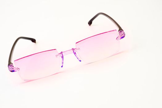 a pair of lenses set in a frame resting on the nose and ears, used to correct or assist defective eyesight or protect the eyes. Pink glasses for vision on a white background.