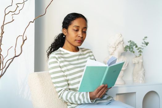 African-american female reading book in free time. Unplugged break. Slow paced lifestyle. Concept of modern young bookworm. Focusing on literature. Finding inspiration while relaxing