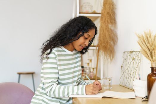 African-american woman taking notes in notebook. Making lists. Planning life in diary. Concepf of slow living lifestyle. Writing down thoughts and feelings. Sharing emotions on paper. State of mindset
