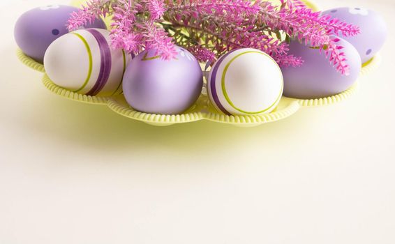 Easter concept lilac Easter eggs with a branch of artificial lavender on a light background. Place for your text.