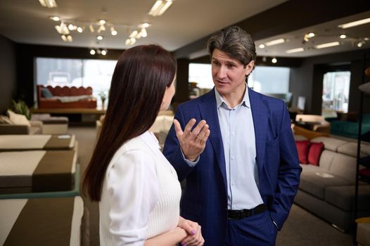 A middle aged Caucasian couple, husband and wife choosing upholstered furniture in a furniture mall.