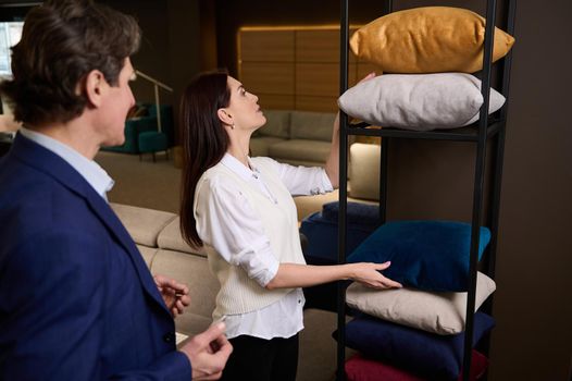 Middle aged Caucasian married couple selecting new sofa pillows and cushions in the showroom of a furniture store. Home improvement, home comfort and interior design