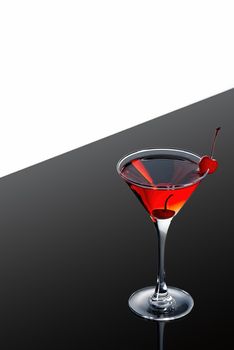 red martini cocktail on a dark background fading in to black garnished with a red cherry