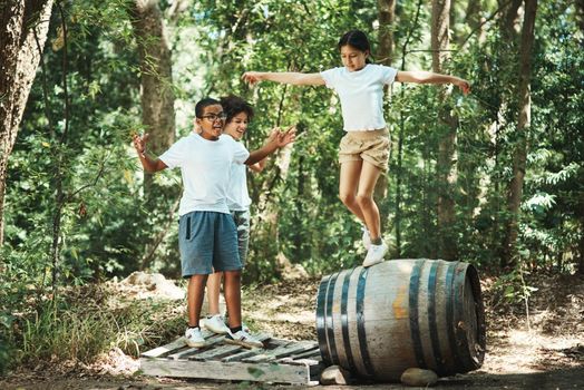 Shot of a group of teenagers having fun with a barrel in nature at summer camp.