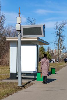 A woman is standing at a bus stop waiting for transport.