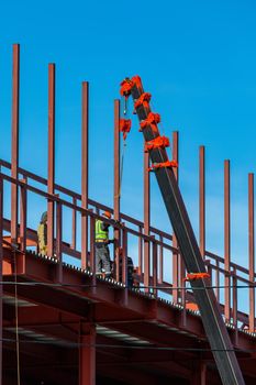 Builders fix iron beams with a crane. Frame construction.