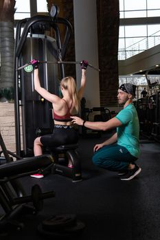 RUSSIA, MOSCOW - FEB 11, 2022: A girl is engaged in a led press simulator in a red blonde beautiful on a black background leg gym training man muscles, from lifting workout from weight for exercise bodybuilder, power male. Girl female active, sporty trainer